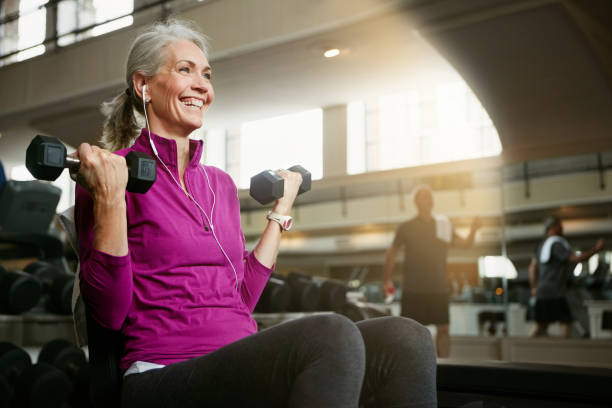 Portrait of a happy senior woman working out with weights at the gym